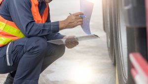 Person inspecting a truck and looking at a clipboard