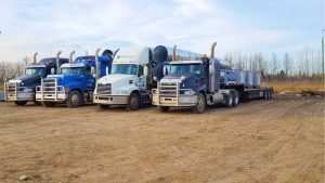 Four trucks parked on sandy road.