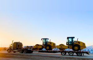 Truck carrying smaller vehicles with a sunset backgrop